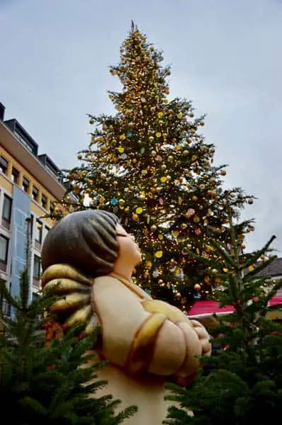 Mercatini di Natale Bolzano angioletto della Thun davanti ad un albero addobbato