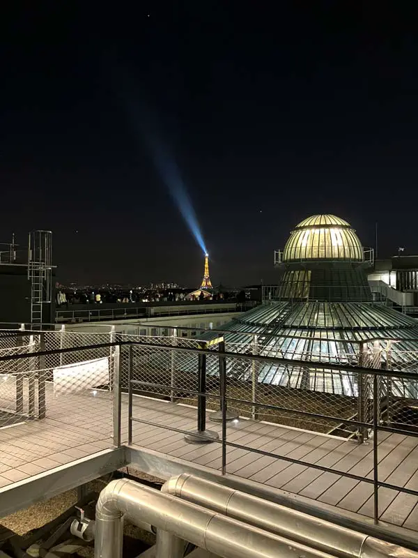Terrazza della galerie la fayette a Parigi con vista sulla torre eiffel illuminata di notte